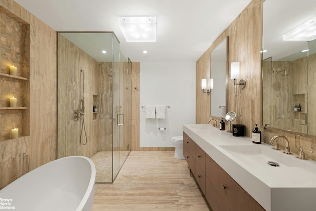 full bath featuring toilet, a stall shower, a freestanding bath, and a sink