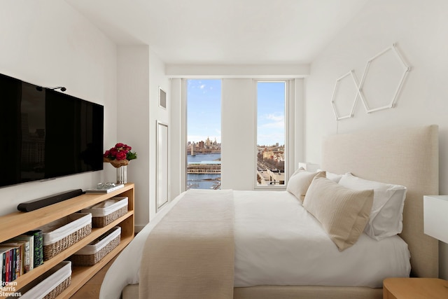 bedroom with visible vents and a water view