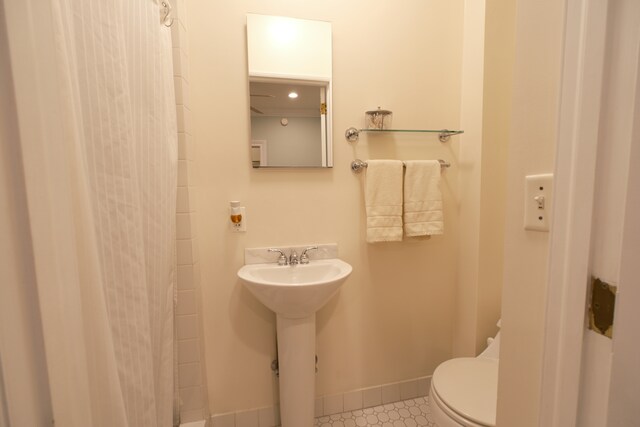 full bath featuring toilet, tile patterned flooring, a sink, a shower with curtain, and baseboards