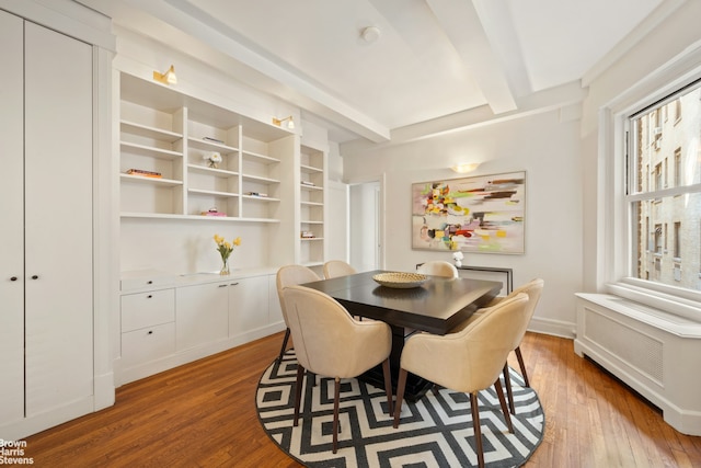 dining area with radiator, wood-type flooring, and beamed ceiling