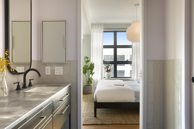 bedroom featuring a sink and tile walls