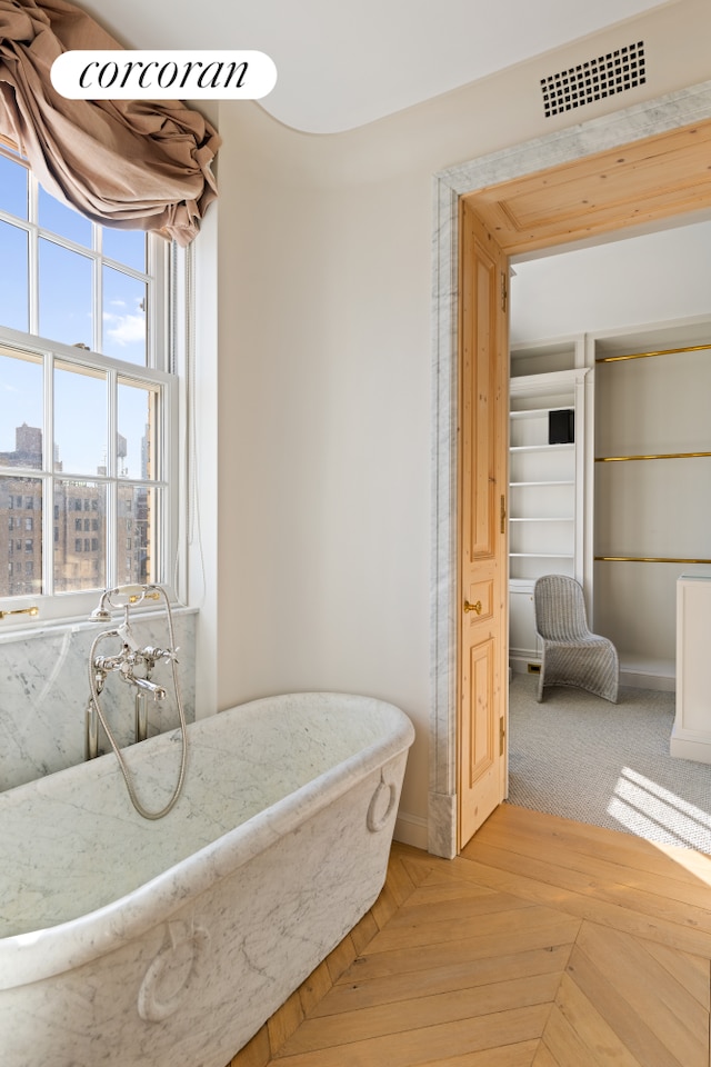 bathroom featuring visible vents and a freestanding bath