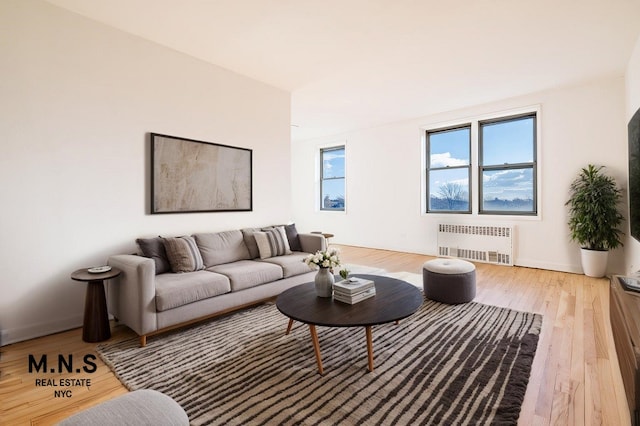 living area featuring hardwood / wood-style floors, radiator heating unit, and baseboards