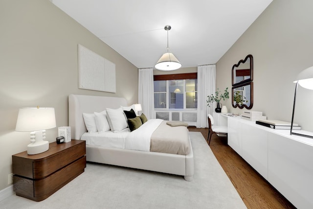 bedroom with lofted ceiling and wood finished floors