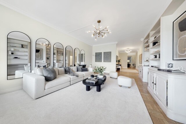 living area with baseboards, an inviting chandelier, built in features, and crown molding