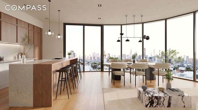 dining area featuring a healthy amount of sunlight, light wood-style floors, expansive windows, and a city view