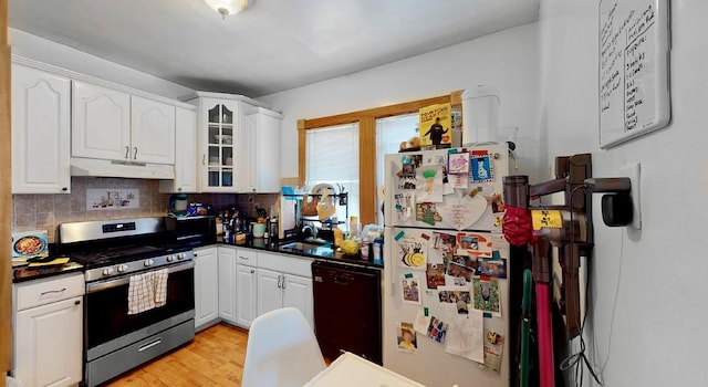 kitchen with stainless steel gas range oven, under cabinet range hood, dark countertops, freestanding refrigerator, and dishwasher