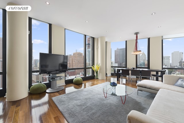 living area with recessed lighting, a healthy amount of sunlight, floor to ceiling windows, and hardwood / wood-style flooring