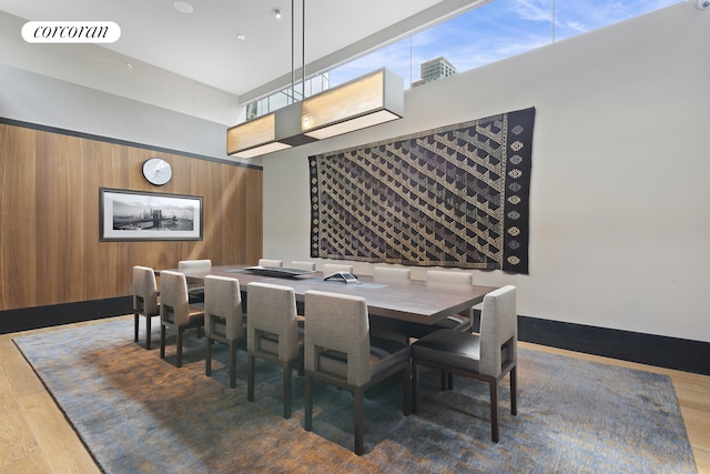 dining space with visible vents, wood finished floors, a towering ceiling, and wooden walls