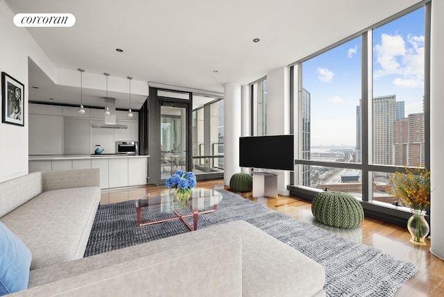 living room with expansive windows, light wood-type flooring, and visible vents