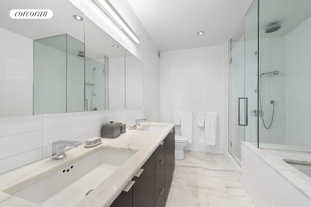 full bath featuring a stall shower, a sink, tile walls, and toilet