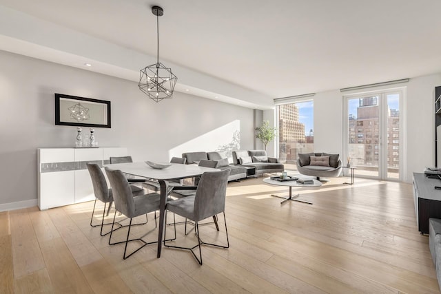 dining room featuring a city view, recessed lighting, light wood-type flooring, and baseboards