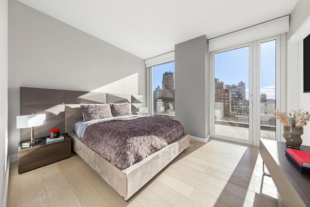 215 W 28th St Unit 14C, New York City, NY 10001 - bedroom with a view of skyline, light wood-style floors, and access to exterior