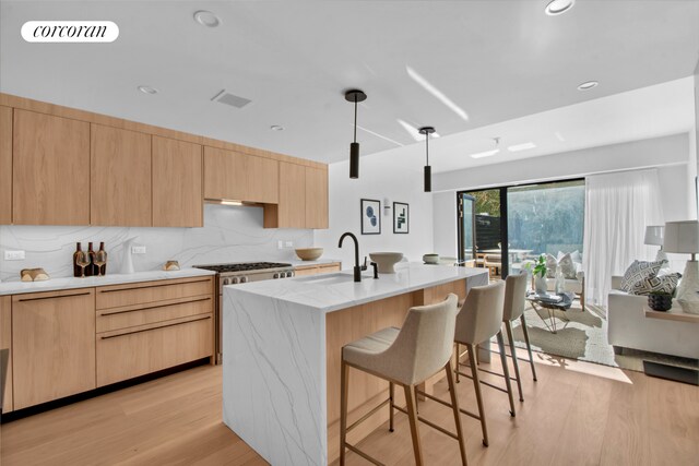 kitchen with light wood-style floors, light brown cabinets, a sink, and a kitchen breakfast bar