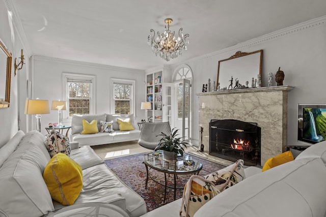 living area featuring crown molding, a notable chandelier, and a premium fireplace