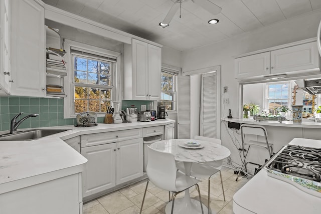 kitchen with decorative backsplash, light countertops, white cabinets, and a sink