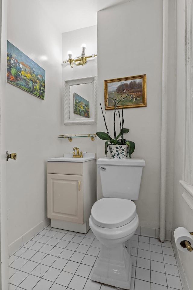 half bathroom with tile patterned floors, toilet, vanity, and baseboards