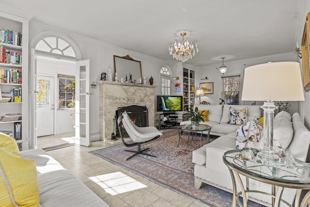 living area with tile patterned flooring, crown molding, a notable chandelier, and a premium fireplace