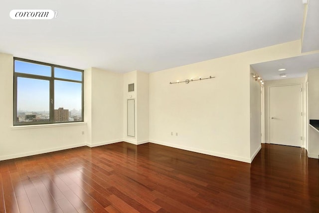 spare room with wood finished floors, visible vents, and baseboards