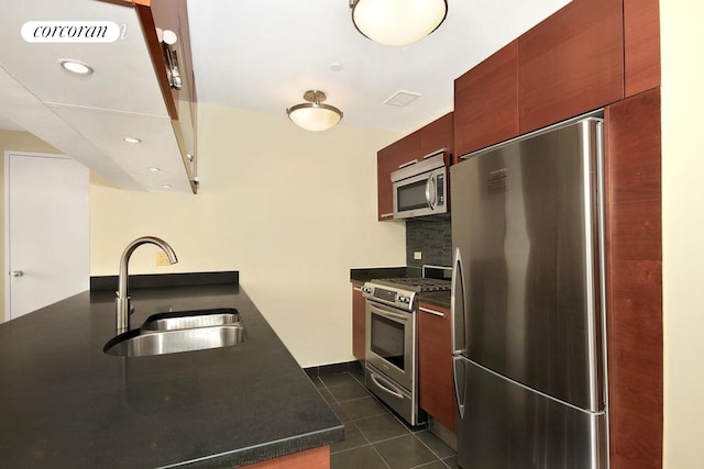 kitchen featuring appliances with stainless steel finishes, dark countertops, a sink, and tasteful backsplash