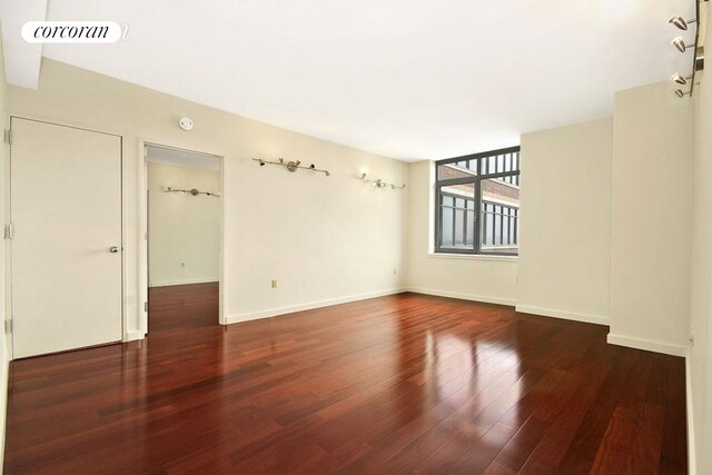 empty room featuring wood finished floors, visible vents, and baseboards