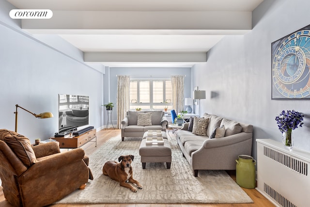 living area with beam ceiling, visible vents, radiator heating unit, and wood finished floors