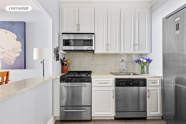 kitchen featuring backsplash, white cabinetry, stainless steel appliances, and a sink