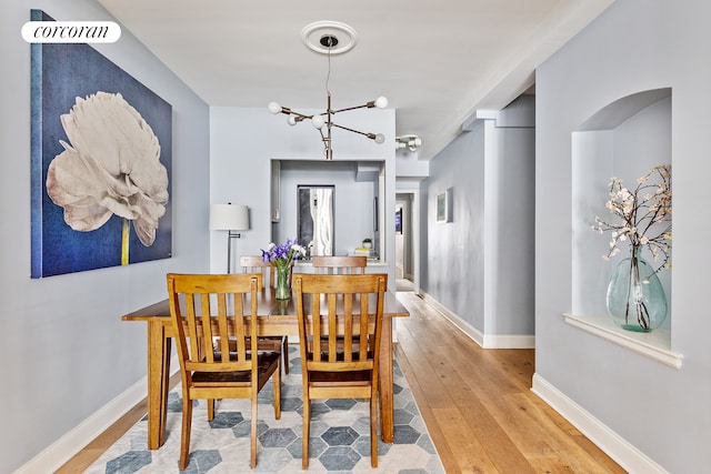 dining space with hardwood / wood-style floors, a notable chandelier, and baseboards