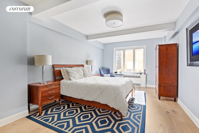 bedroom with beamed ceiling, radiator, baseboards, and light wood-style floors