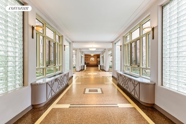 hallway featuring crown molding, baseboards, and plenty of natural light