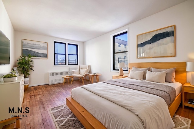 bedroom with wood-type flooring, radiator, and baseboards