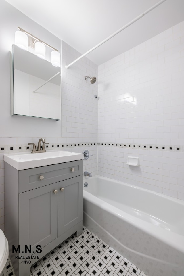 full bath with vanity, toilet, tile patterned floors, tile walls, and  shower combination