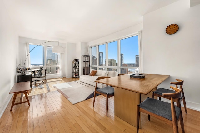 350 W 42nd St Unit 37H, New York City, NY 10036 - dining room featuring light wood-style floors, a view of skyline, and baseboards