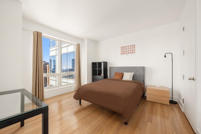 bedroom featuring light wood-style flooring and a city view