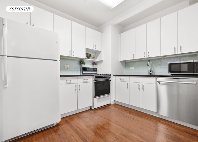 kitchen with dark countertops, light wood-style floors, white cabinets, and stainless steel appliances