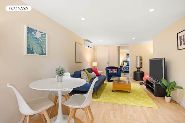 living room featuring a wall unit AC, light wood finished floors, visible vents, and recessed lighting