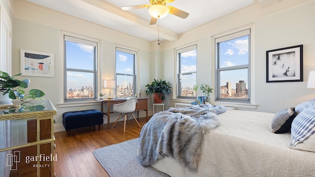 bedroom with a ceiling fan, beamed ceiling, hardwood / wood-style flooring, and baseboards