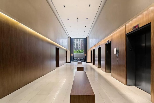 hallway with elevator, wood walls, and floor to ceiling windows