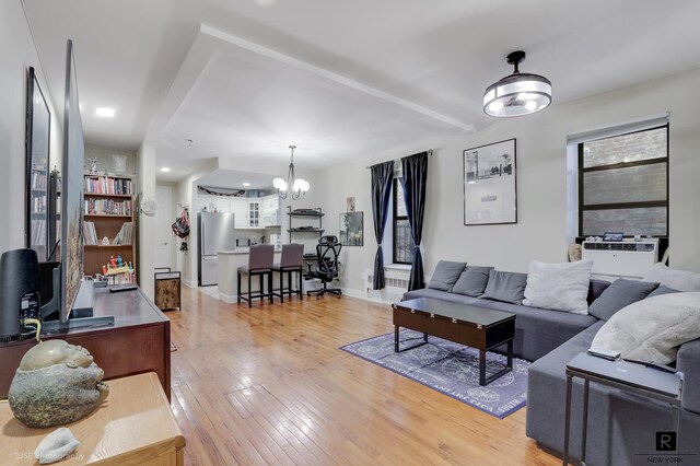 living area with light wood-style floors, baseboards, a chandelier, and cooling unit