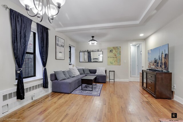 living room with baseboards, light wood finished floors, radiator heating unit, and an inviting chandelier