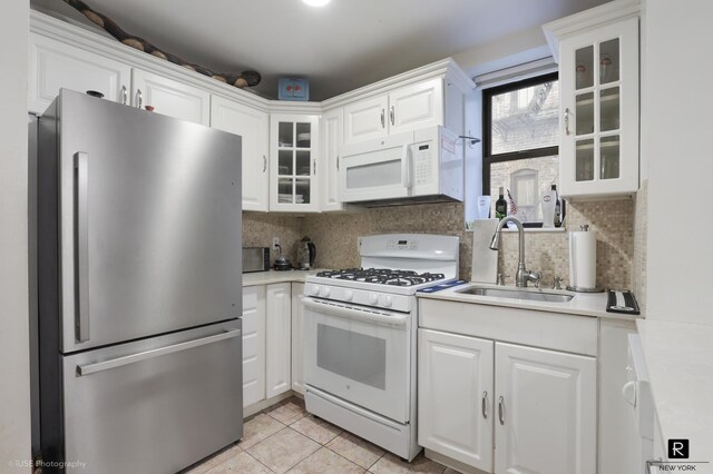 kitchen featuring light countertops, backsplash, white cabinetry, a sink, and white appliances