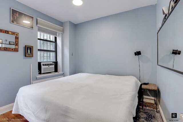 bedroom with cooling unit, wood finished floors, and baseboards