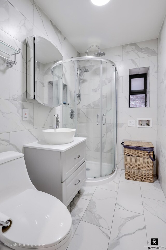 full bath featuring a stall shower, tile walls, marble finish floor, and vanity