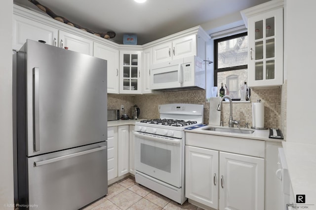 kitchen featuring light countertops, decorative backsplash, white cabinetry, a sink, and white appliances