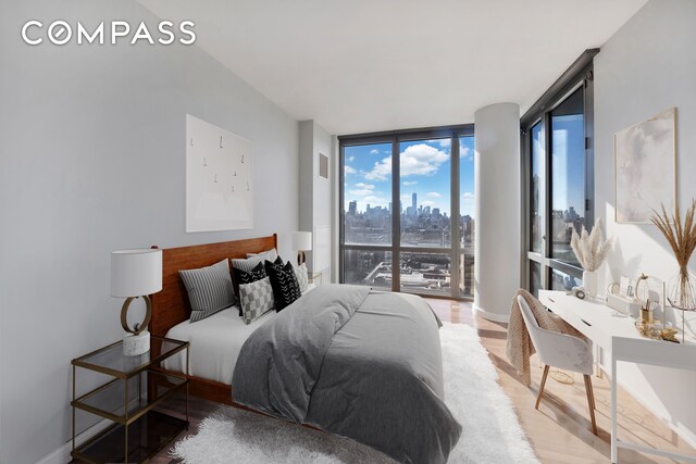bedroom featuring a view of skyline, a wall of windows, wood finished floors, and access to outside