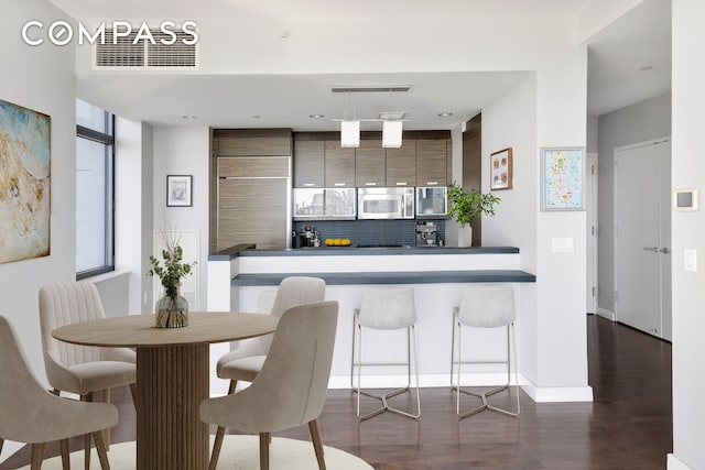 kitchen with tasteful backsplash, visible vents, stainless steel microwave, and dark wood-type flooring