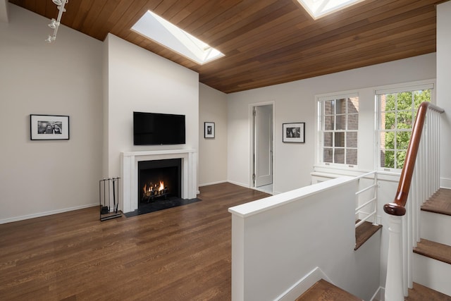 living room with dark wood finished floors, lofted ceiling with skylight, a fireplace with flush hearth, and wooden ceiling