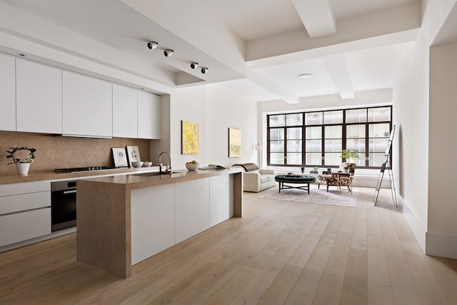 kitchen with tasteful backsplash, beamed ceiling, white cabinetry, modern cabinets, and stainless steel oven
