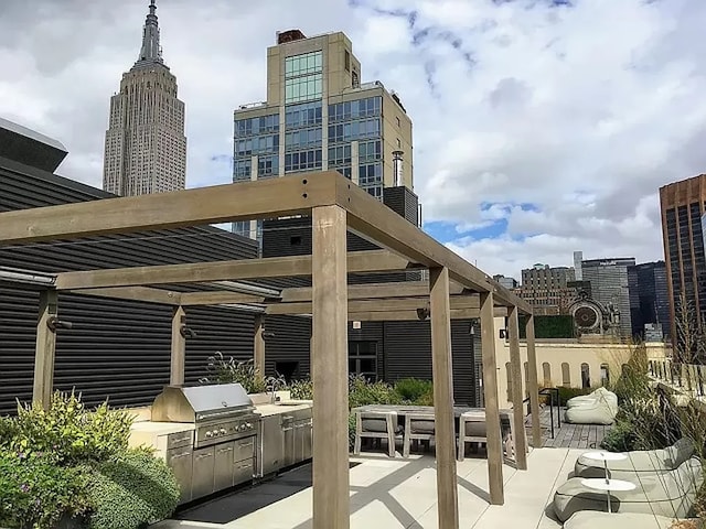 view of patio / terrace featuring a grill, an outdoor kitchen, a city view, and a pergola