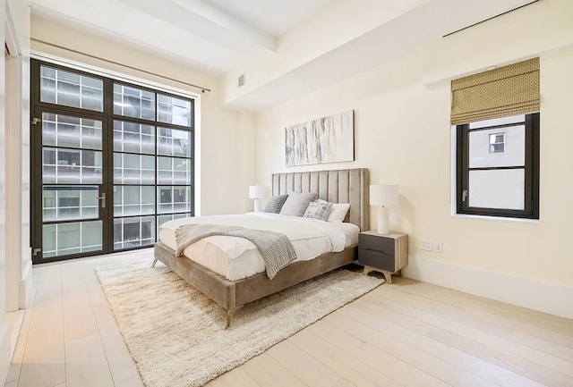 bedroom with wood finished floors and beam ceiling